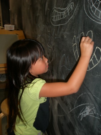 Kasen drawing on a chalkboard